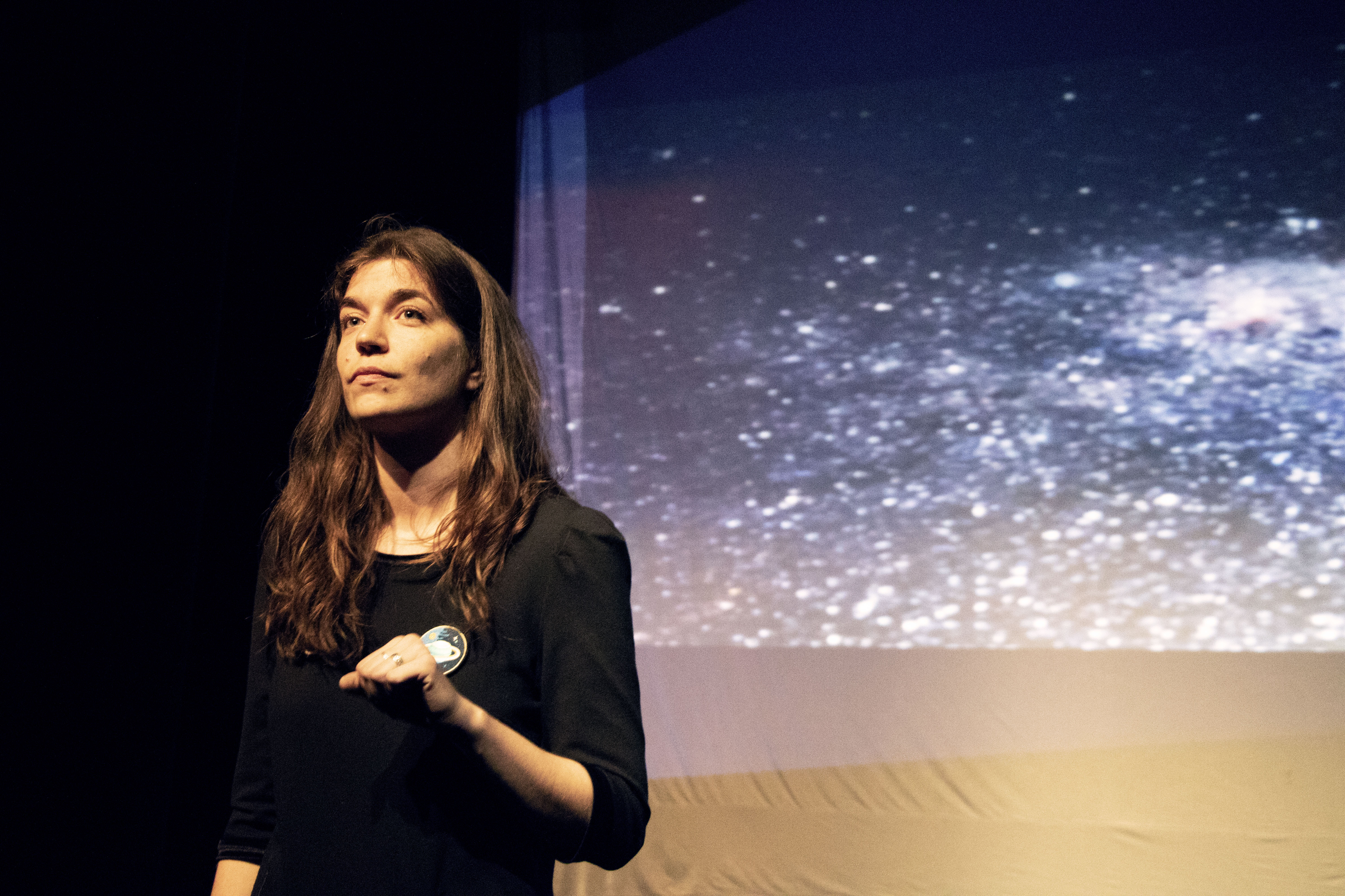 Emanuelle Caron, une des comédienne, devant l'écran vidéo avec projection d'étoiles.