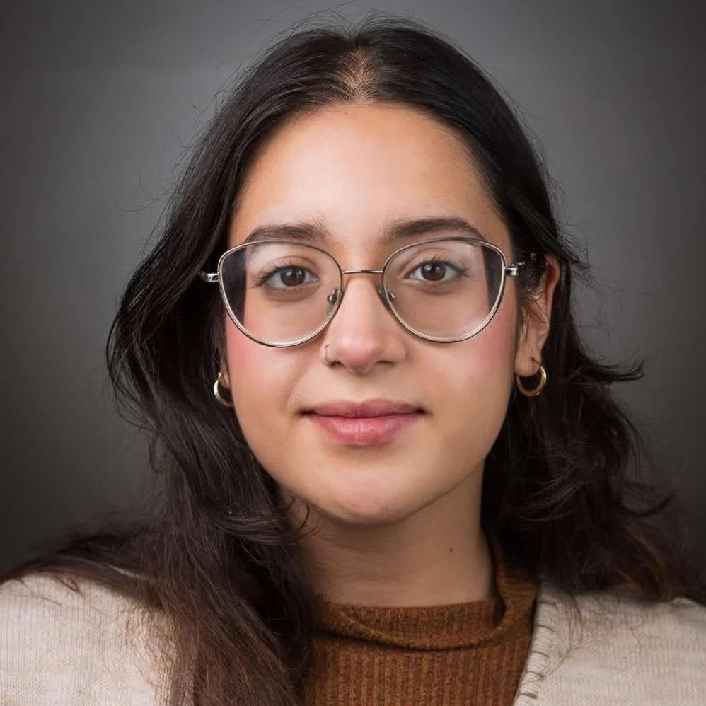 Portrait d'une femme, cheveux noirs, yeux bruns et lunette et souriante.
