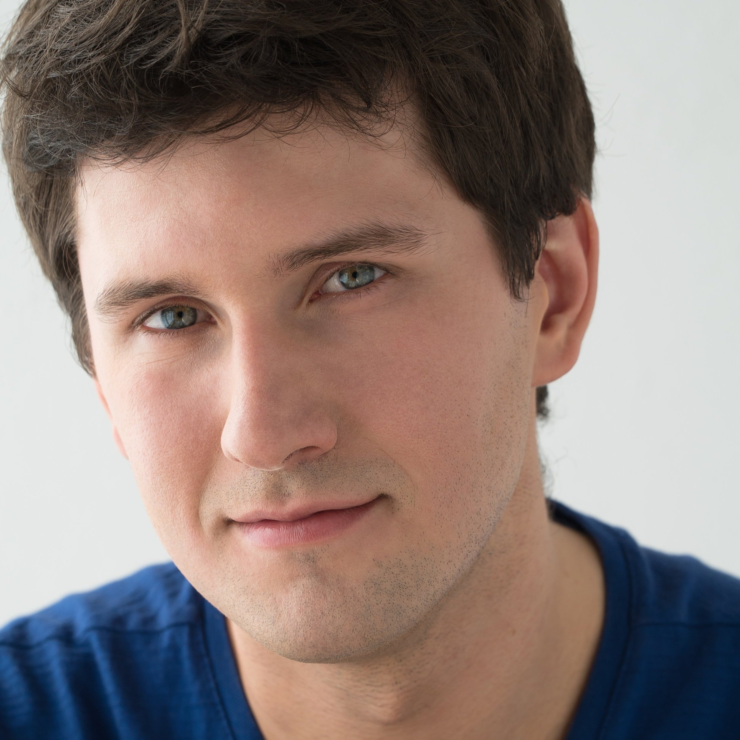 Portrait d'un homme, cheveux brun, yeux bleus et souriant.