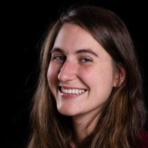 Portrait d'une femme souriante, cheveux longs châtains et yeux bleus.