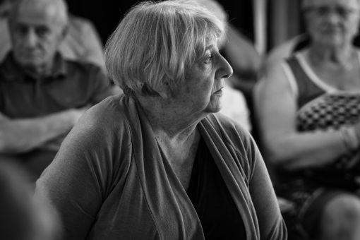 Portrait d'une comédienne, regard tournée vers le lointain, le public derrière elle suit la scène.